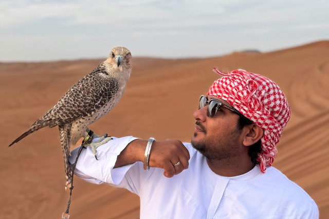 A Qatari man holding a falcon on his arm, showcasing the traditional art of falconry.