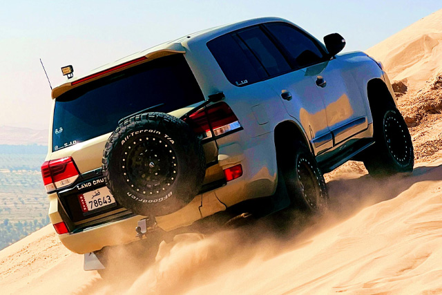 A 4x4 vehicle driving over golden sand dunes, representing the Best Desert Adventures in Qatar