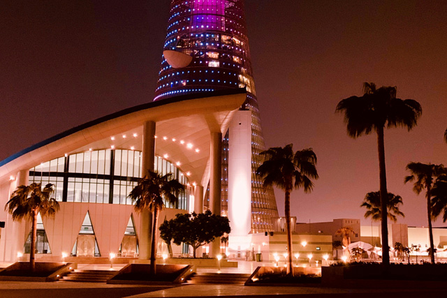A stunning night view of The Torch Tower in Doha, Qatar, illuminated with vibrant lights, a must-see landmark featured in our Qatar Travel Guide.